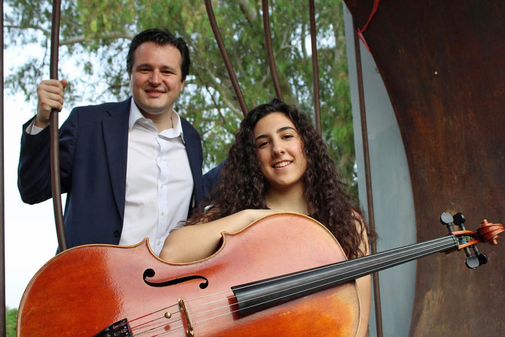 Clara Gresa sosteniendo su violonchelo sentado y Tommaso Cogato detrás de pie